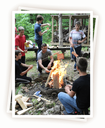 Campers grilling around fire